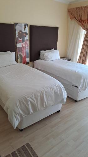two beds in a hotel room with white sheets at Phokela Guest House in Mokopane