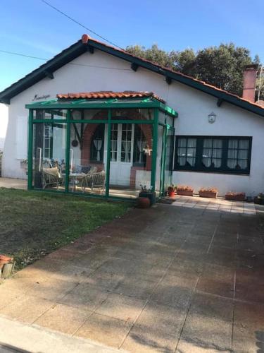 un cenador verde frente a una casa en Villa refaite à neuf à 200 mètres de la plage en Soulac-sur-Mer