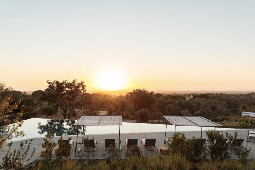 a pool with chairs and the sunset in the background at Pa.te.os in Melides