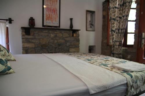 a white bed in a bedroom with a brick wall at Eski Datça Pansiyon in Datca