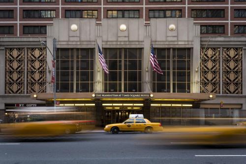 um táxi amarelo em frente a um edifício com bandeiras americanas em The Manhattan at Times Square em Nova Iorque