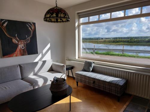 a living room with a couch and a large window at Entre Deux Eaux in Lanaken