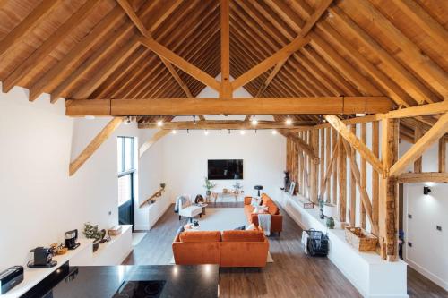 una sala de estar de planta abierta con techos y vigas de madera. en The Honeybee's Nest - Semi-rural Barn Conversion close to Leavesden Studios, en Leverstock Green