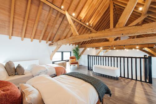two beds in a room with wooden ceilings at The Honeybee's Nest - Semi-rural Barn Conversion close to Leavesden Studios in Leverstock Green