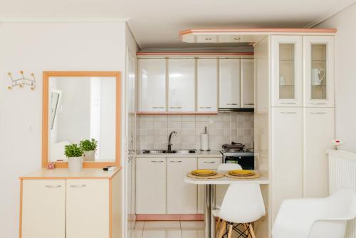 uma cozinha com armários brancos e uma mesa em CACTUS - Blooming Garden Apartments em Kalamata