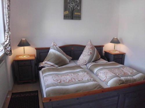 een slaapkamer met een bed met kussens en 2 lampen bij Appartementhaus Viktoria in Bad Birnbach