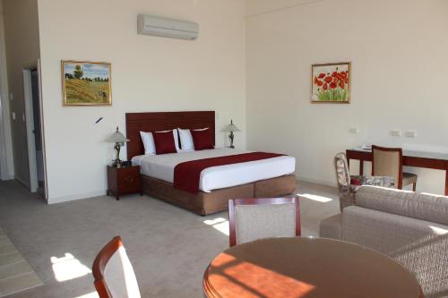 a bedroom with a bed and a couch and a table at Quality Hotel Regent Rockhampton in Rockhampton