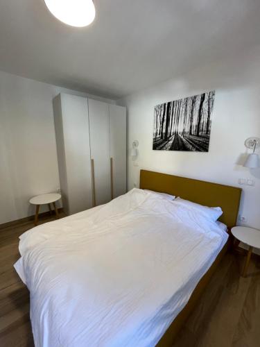 een slaapkamer met een groot wit bed en 2 tafels bij Sunshine Apartments Golte E4 in Mozirska Koča