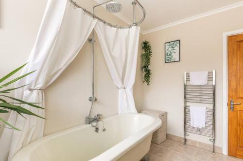 a white bath tub in a bathroom with a window at Eighteen Whitstable 4 parking spaces in Kent