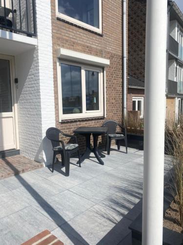 a patio with three chairs and a table and a building at Apartment de Boer in Zandvoort