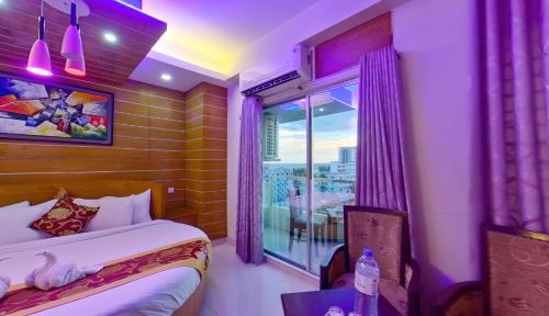 ein Schlafzimmer mit einem Bett und einem Fenster mit violetten Lichtern in der Unterkunft Hotel Sea Cox in Cox's Bazar