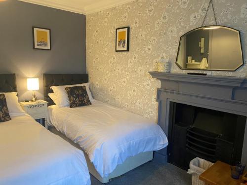 a bedroom with two beds and a fireplace with a mirror at Talbot House Bed & Breakfast and Tearoom in Pateley Bridge
