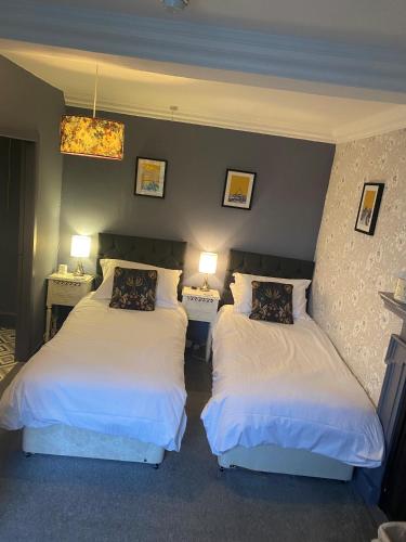 two beds in a room with two lamps on the wall at Talbot House Bed & Breakfast and Tearoom in Pateley Bridge