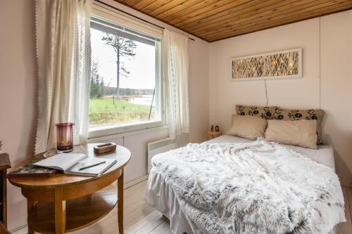 um quarto com uma cama, uma secretária e uma janela em Lapland Sunrise Cottage with lakefront Sauna em Rovaniemi