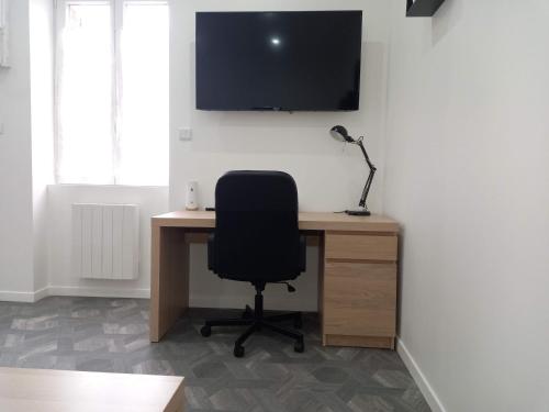 a desk with a chair and a television on a wall at Logements neufs tout équipés, idéal travail mobilité in Le Creusot