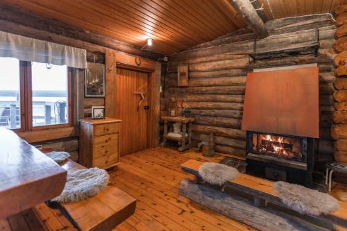 a living room with a fireplace in a log cabin at Lapland Northern Lights Cabin - Wooden Sauna in Rovaniemi