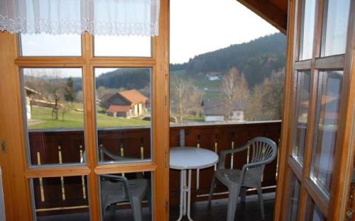 a balcony with a table and chairs and a window at Ferien- und Freizeithof Bindl in Sankt Englmar