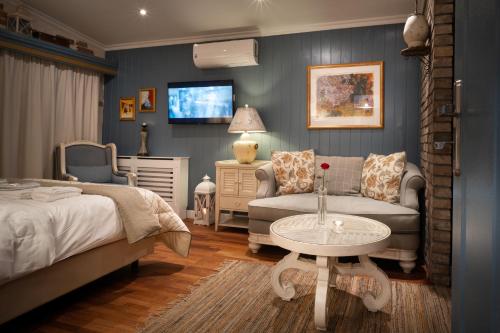 ein Schlafzimmer mit einem Bett, einem Sofa und einem TV in der Unterkunft Paul's Fantasia Boutique Suites in Stettin
