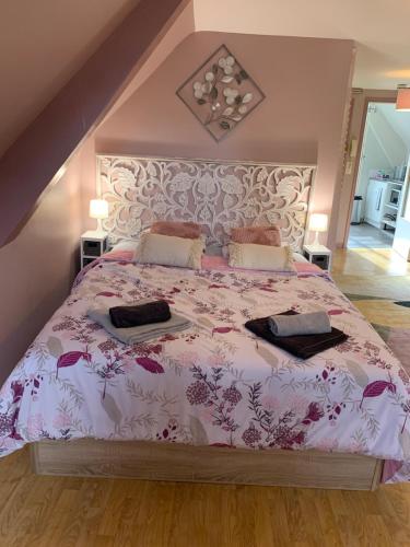 a bedroom with a large bed with a pink comforter at Le Grenier studio de charme centre historique in Dinan