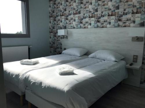 a bedroom with a large bed with white sheets and pillows at The Originals Access, Hôtel les Iris, Berck-sur-Mer in Berck-sur-Mer
