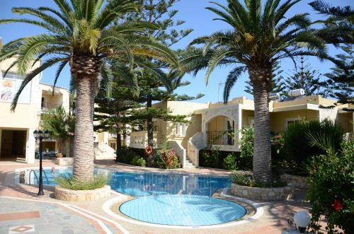 a villa with palm trees in front of a swimming pool at Kastalia Village ,Saint Nikolas resort in Kolymvari