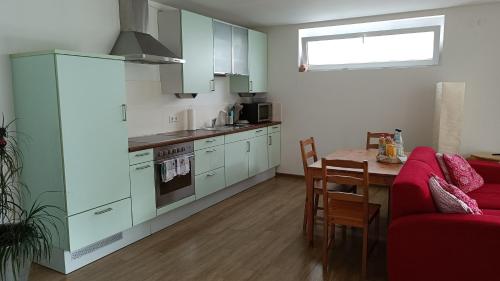eine Küche mit einem roten Sofa und einem Tisch in einem Zimmer in der Unterkunft Apartment Baumeister in Weilheim an der Teck