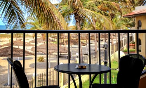 a table and chairs on a balcony with palm trees at Ocean Bay Hotel & Resort in Bathurst