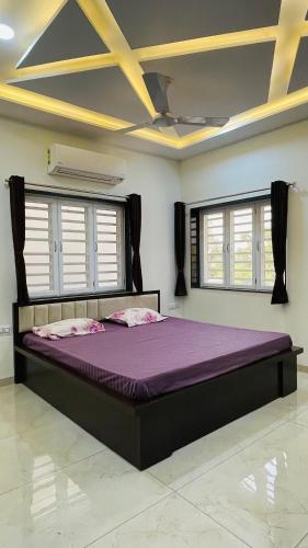 a bedroom with a purple bed in a room with windows at Luxurious 3 BHK Villa In Bhuj - Shivani Homestay in Bhuj