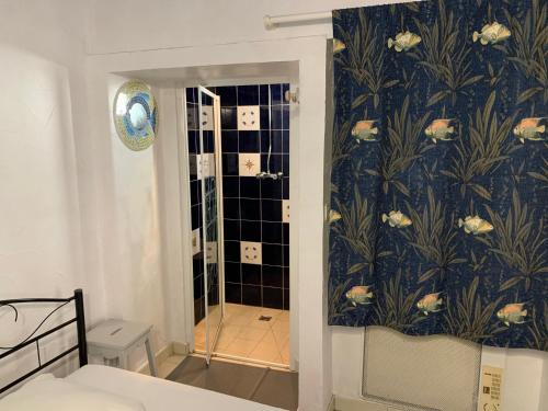 La salle de bains est pourvue d'une douche et de papier peint bleu et blanc. dans l'établissement Maison de pays au centre du village, à Saint-Martin-de-Ré