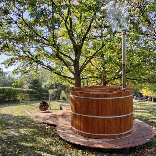 a wooden barrel sitting in a park with a tree at Jurta az erdő mellett dézsával-KERESZ-TANYA in Pilisszentkereszt