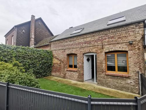 a brick house with a black fence in front of it at Les Arches. in Méneslies