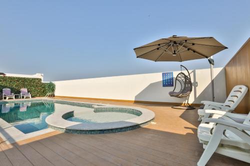 un patio con sombrilla y piscina en A&H Hotel Apartment, en Doha
