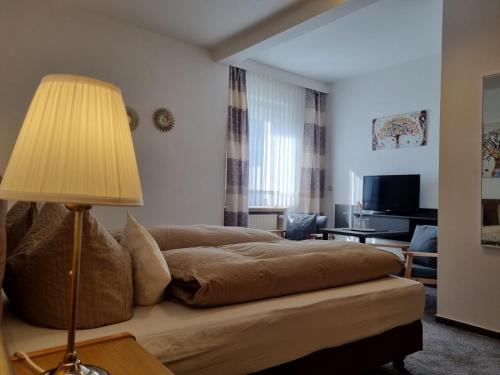 a living room with a bed and a lamp at Sevda's Hotel Garni Weinforth in Willingen