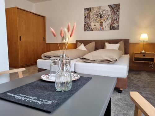 a bedroom with two beds and a table with flowers in a vase at Sevda's Hotel Garni Weinforth in Willingen