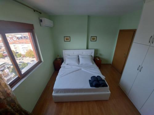 a bedroom with a white bed with a window at Geni Apartment in Korçë
