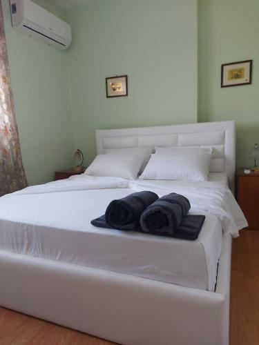 a white bed with two black towels on it at Geni Apartment in Korçë