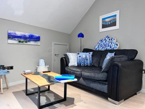 a living room with a black couch and a table at River Vista Retreat - Luxury duplex Apt - Views - Parking - Cycle storage - Spa access option in Backbarrow