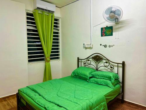 - une chambre avec un lit doté de draps verts et une fenêtre dans l'établissement D'YELLOW HOMESTAY KANGAR PERLIS, à Kangar