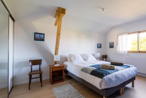 een slaapkamer met een groot bed en een stoel bij La Petite Croix Bienvenue in Saint-Cast-le-Guildo