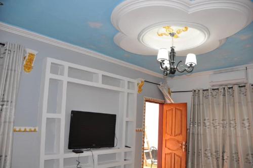 Cette chambre dispose d'un plafond avec une télévision et un lustre. dans l'établissement Appartements meublés haut Standing, à Bertoua