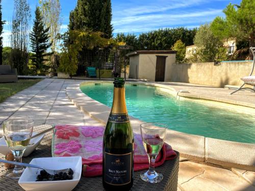eine Flasche Wein und Gläser auf einem Tisch in der Nähe eines Pools in der Unterkunft Suis Le Soleil in Brézilhac