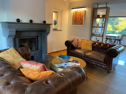 a living room with leather couches and a fireplace at Chambres d’hôtes les Grisons in Houyet