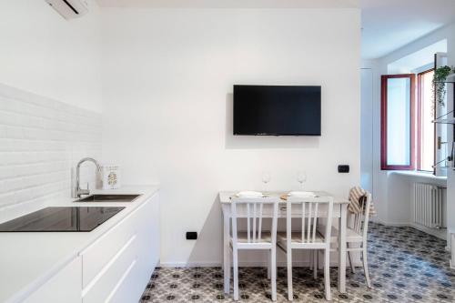 a kitchen with a table and a tv on the wall at Cesare 22 - The House Of Travelers in Como