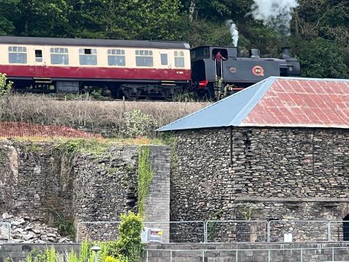 a train traveling down the tracks next to a building at River Vista Retreat - Luxury duplex Apt - Views - Parking - Cycle storage - Spa access option in Backbarrow