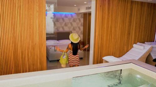 a girl wearing a hat standing in a room with a swimming pool at SG Suite & Spa Amalfi Coast in Vietri