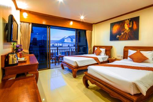 a hotel room with two beds and a balcony at Patong Heaven in Patong Beach