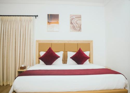 a bedroom with a large bed with red pillows at Quest Boutique Hotel in Gwarinpa