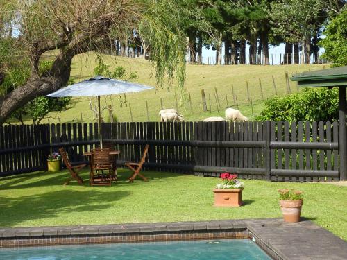 a backyard with a pool and an umbrella and animals at Thorold Country House in Thames