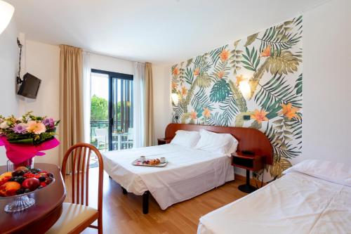 una camera d'albergo con letto e tavolo con vassoio di frutta di Hotel Falcone a Lignano Sabbiadoro