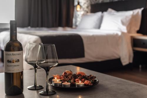 a bottle of wine and a plate of food and two glasses at Ethereal Athεns in Athens